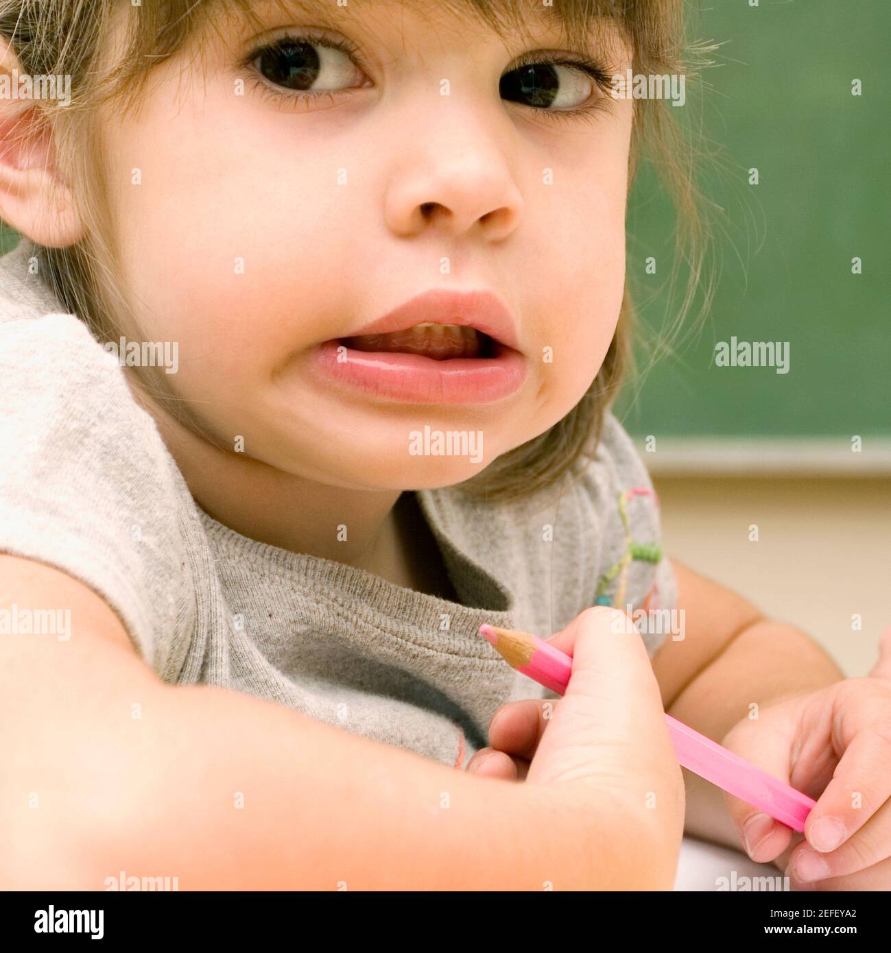 Close up of a girl holding a colored pencil and making a face Stock ...