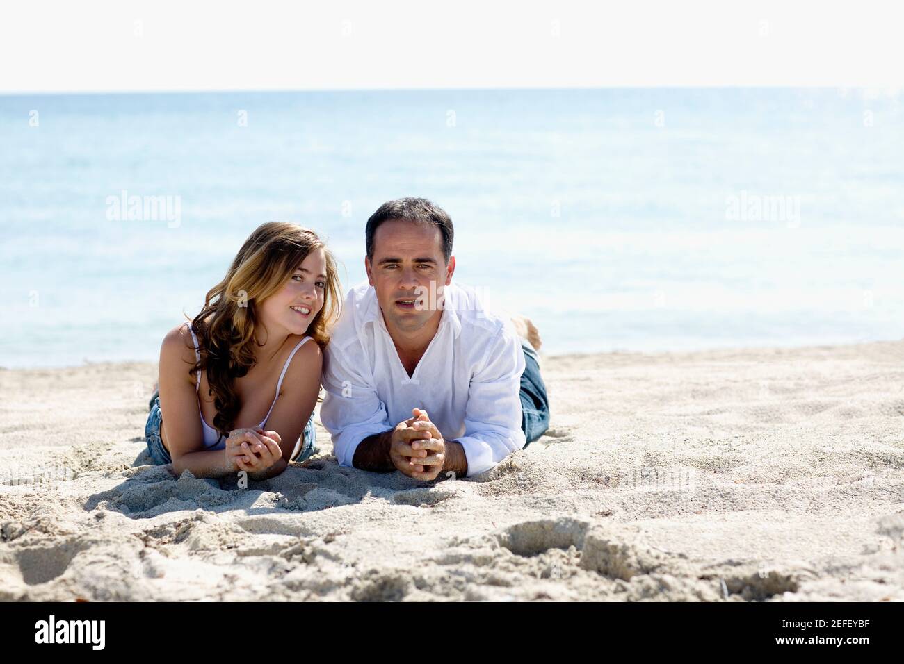 Portrait of a mid adult man and a young woman lying on the beach Stock ...