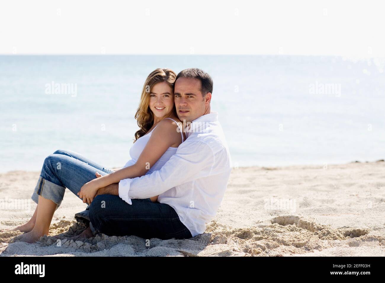Portrait of a young woman sitting on the lap of a mid adult man on the ...