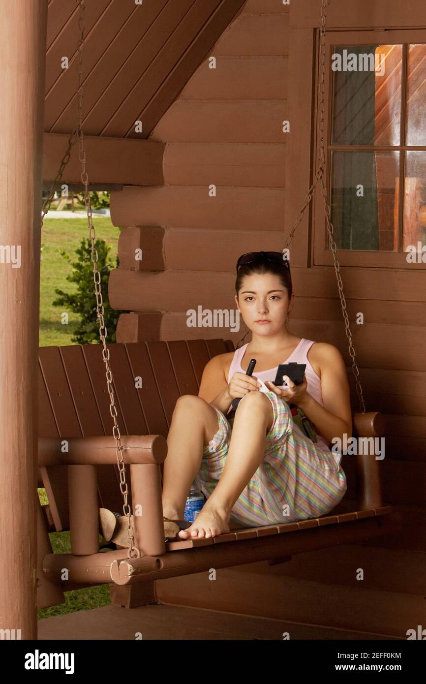 Portrait of a young woman sitting on a swing and holding a makeup brush Stock Photo