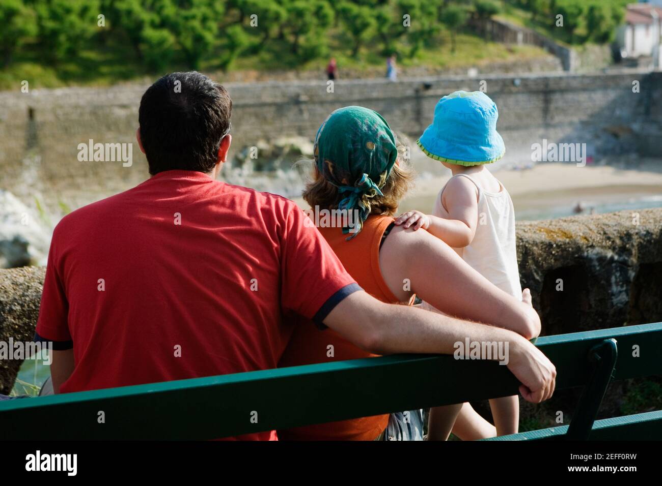 Rear view of a family on a bench, Biarritz, Basque Country, Pyrenees Atlantiques, Aquitaine, France Stock Photo