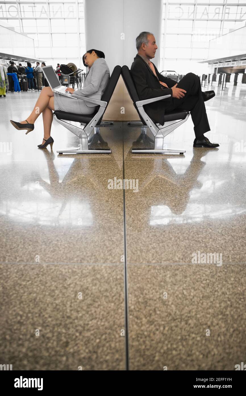 Side profile of a businessman and a businesswoman sitting at an airport lounge Stock Photo