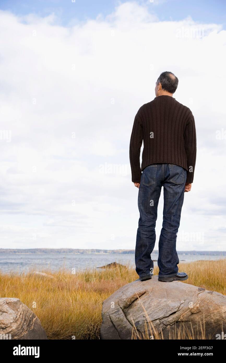 Rear view of a mature man standing on a rock Stock Photo