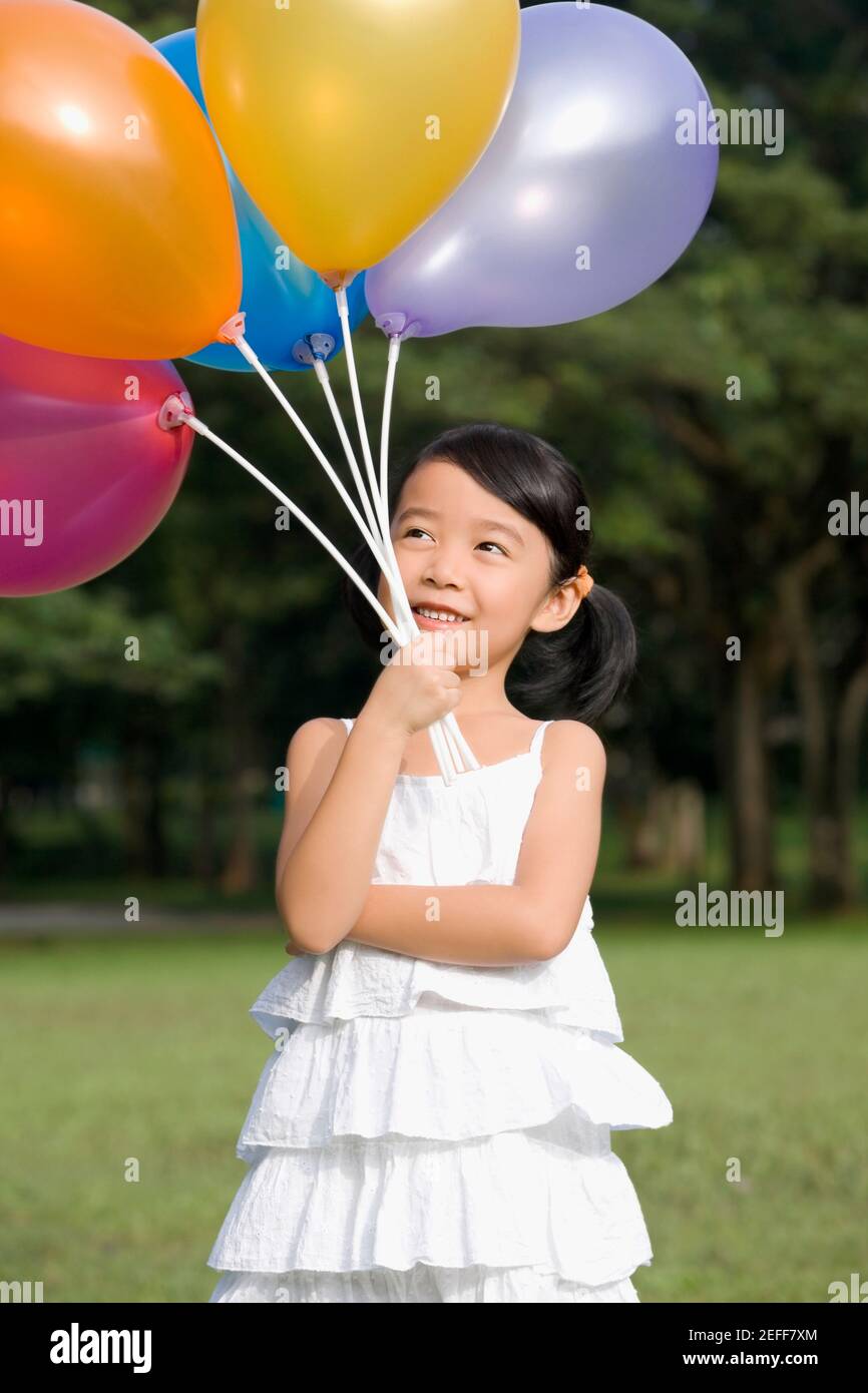 Girl holding balloons and smiling Stock Photo Alamy