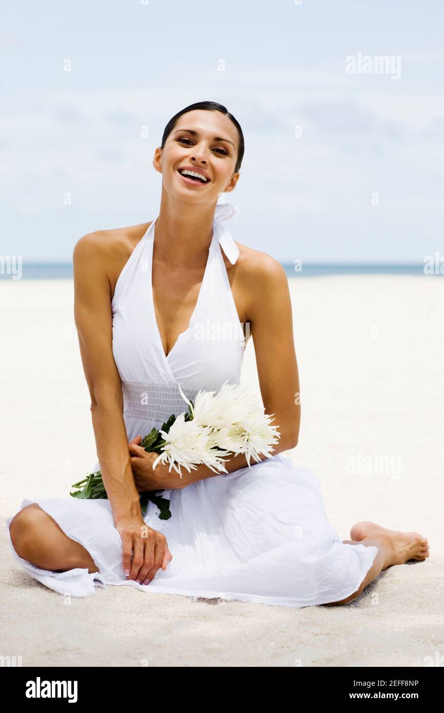 Portrait of a young woman sitting on the beach and smiling Stock Photo ...
