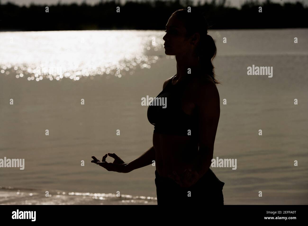 Silhouette of a mid adult woman meditating on the beach Stock Photo - Alamy