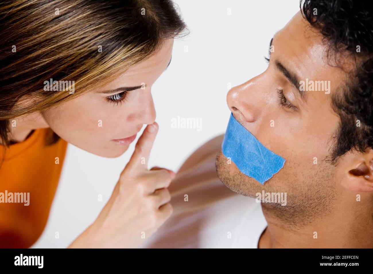 Young man with adhesive tape on his mouth and mid adult woman looking at him Stock Photo