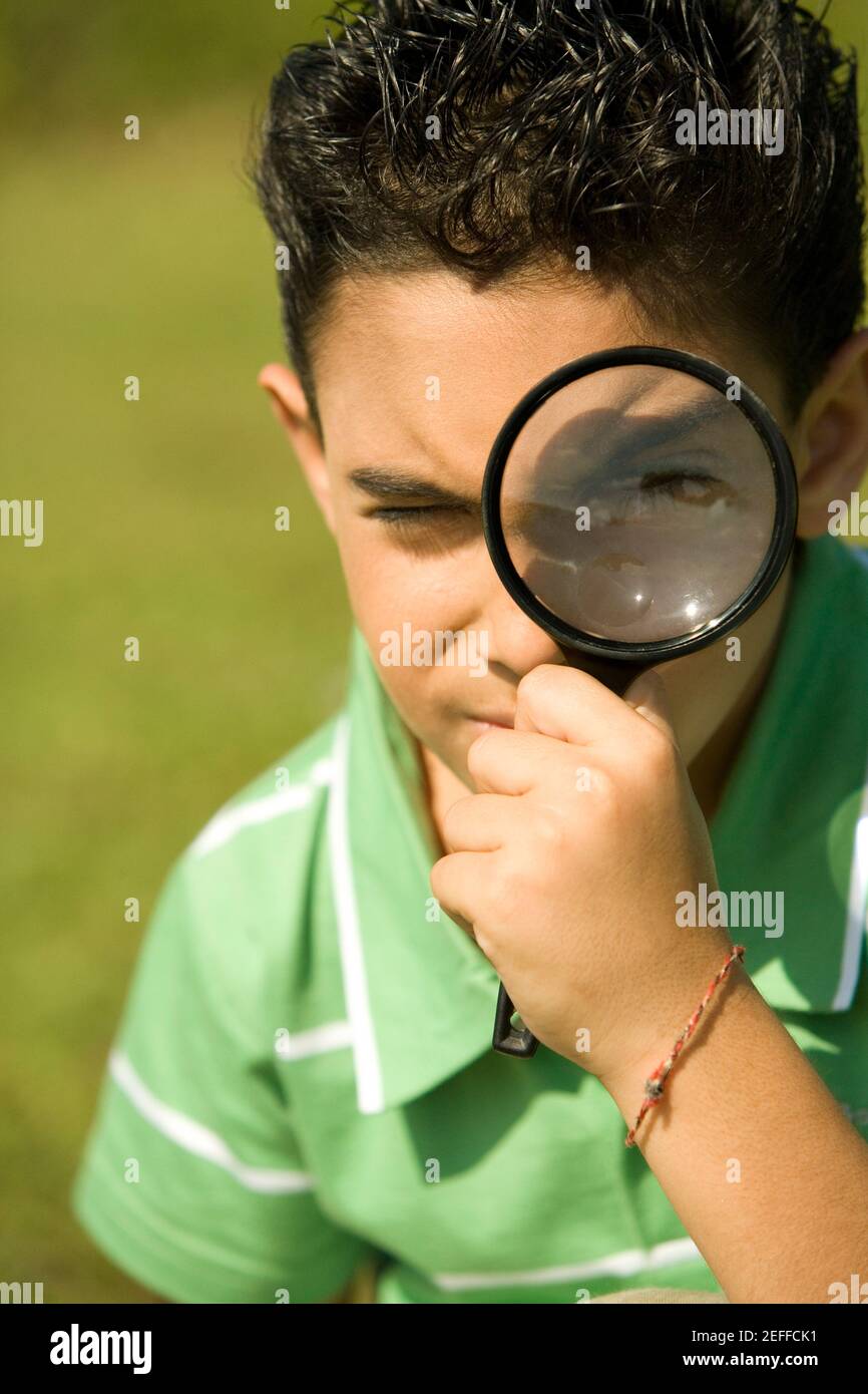 Close-up of a boy looking through a magnifying glass Stock Photo