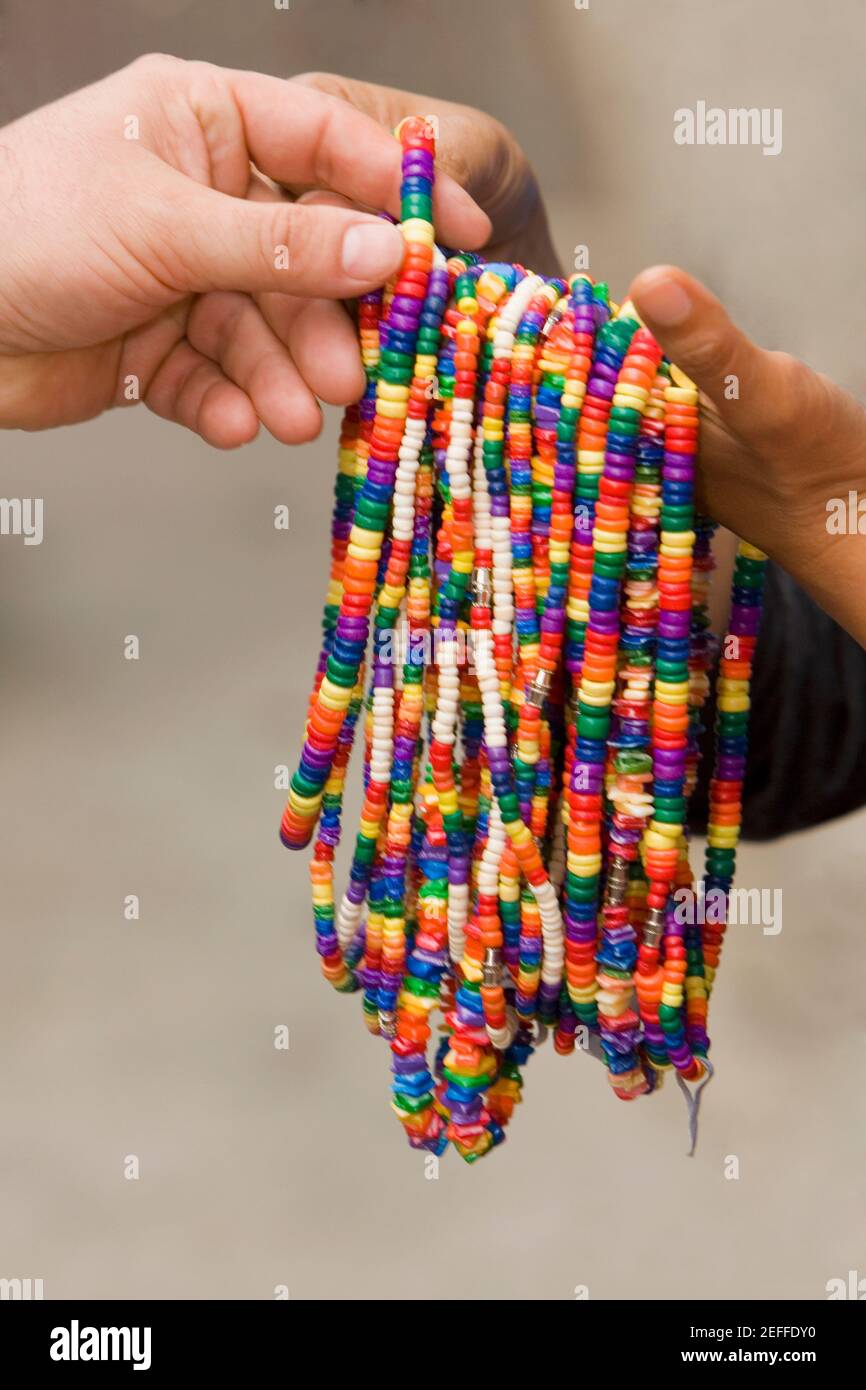 Close-up of two peopleÅ½s hands holding necklaces Stock Photo