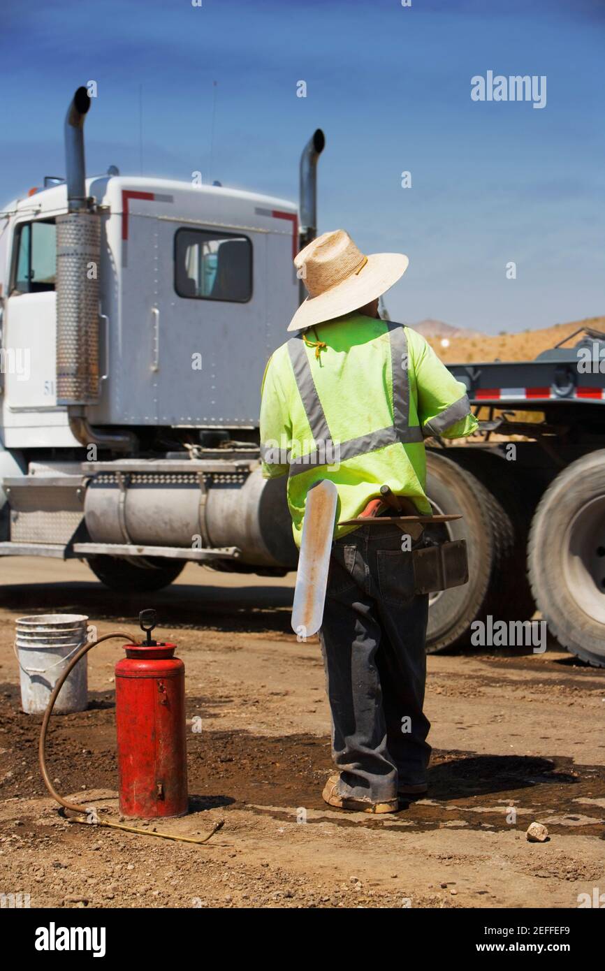 Rear view of a construction worker standing in front of a cement truck Stock Photo