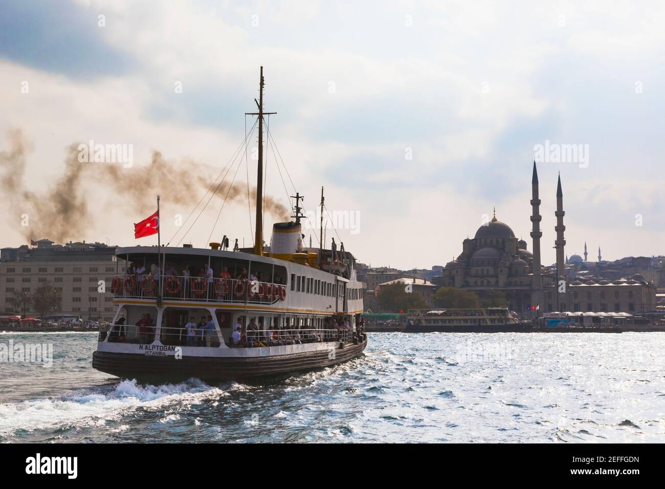 Istanbul, Turkey.  Ferry steaming into Eminönü port.  Yeni Cami, or the New Mosque in background. Stock Photo