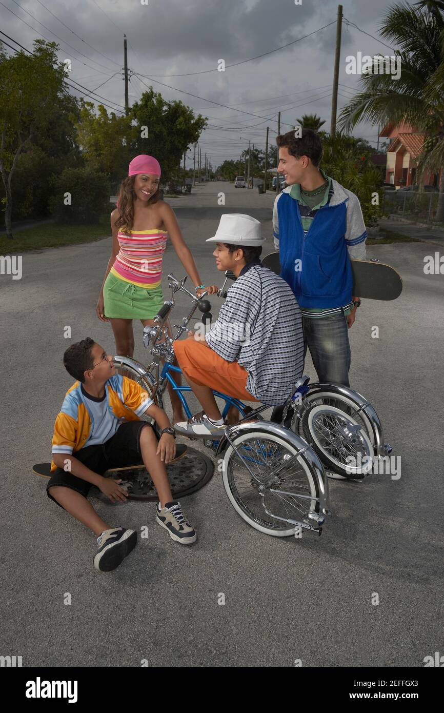 Teenage boy on a low rider bicycle with his three friends beside him Stock Photo