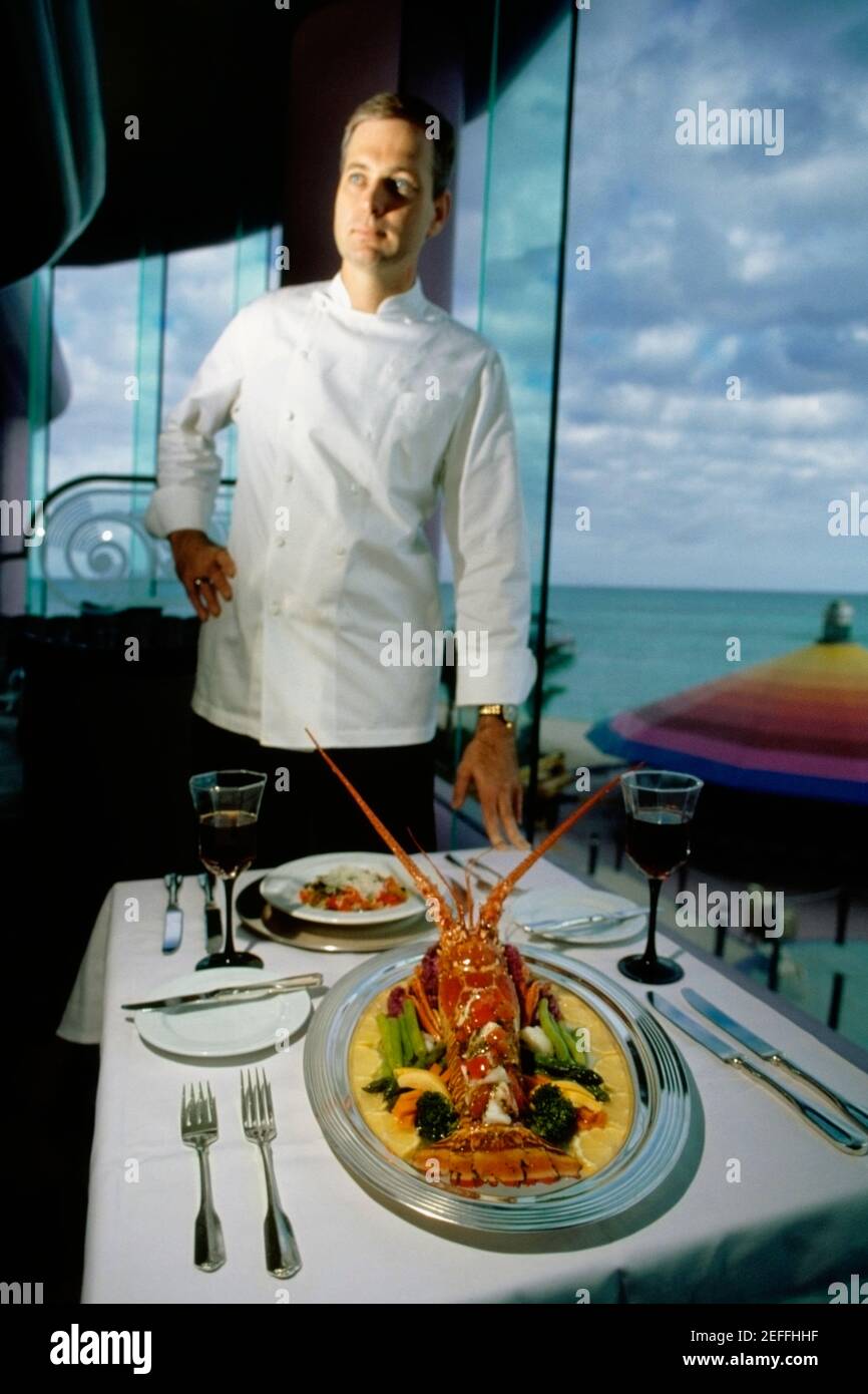 A chef stands near a garnished lobster served on a table, Crystal Palace, Sole Mara, Nassau, Bahamas Stock Photo