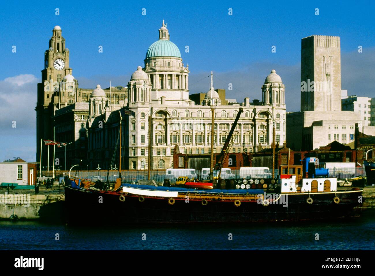 A barge docked beside a domed building and a clock tower, Liverpool, England Stock Photo