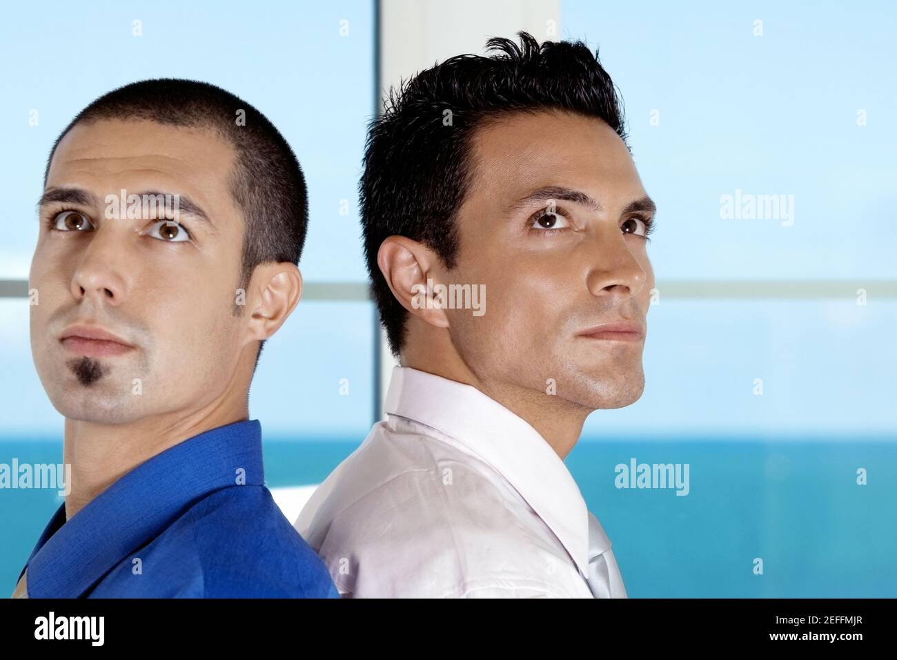 Side profile of two businessmen standing back to back Stock Photo - Alamy