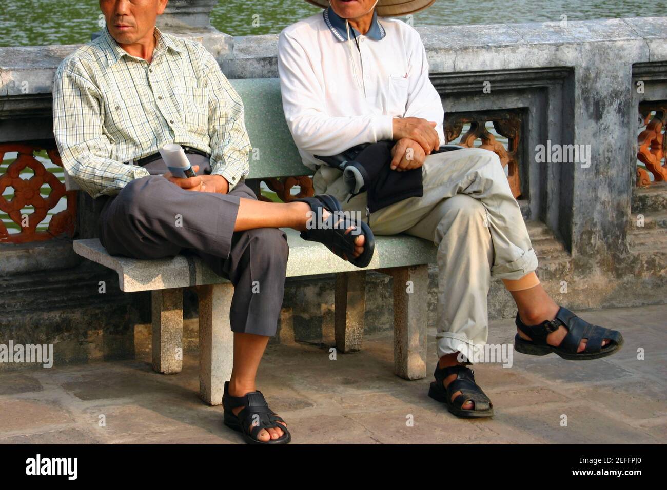 Two mature men sitting on a bench, Hanoi, Vietnam Stock Photo