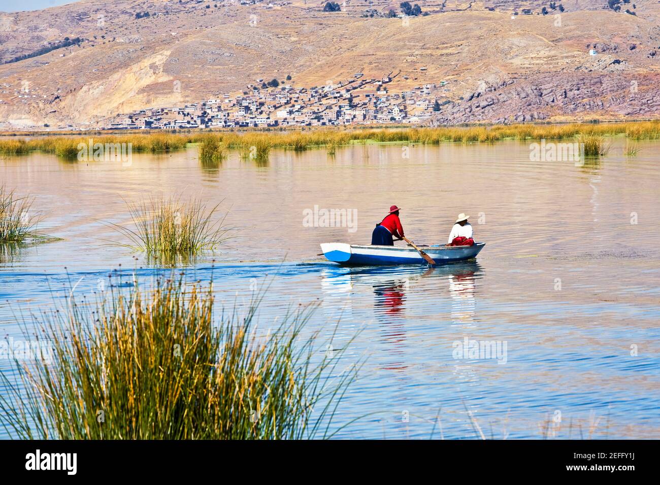 Two people rowing a boat in a lake, Lake Titicaca, Puno, Puno Region, Puno Province, Peru Stock Photo