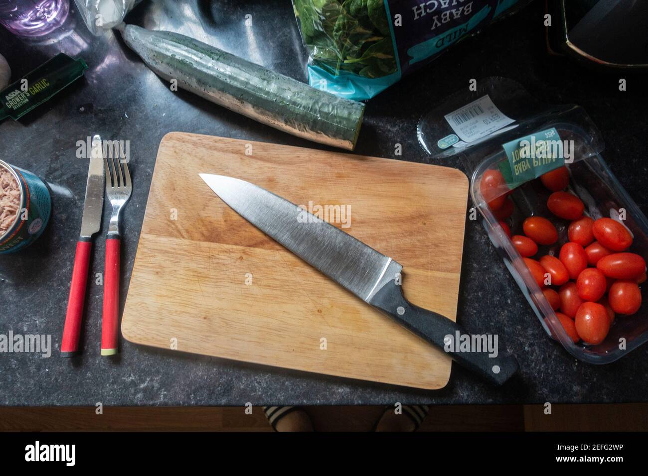 Looking down at a kitchen knife on a wooden chopping board on a kitchen worktop ready to prepare some food. Stock Photo