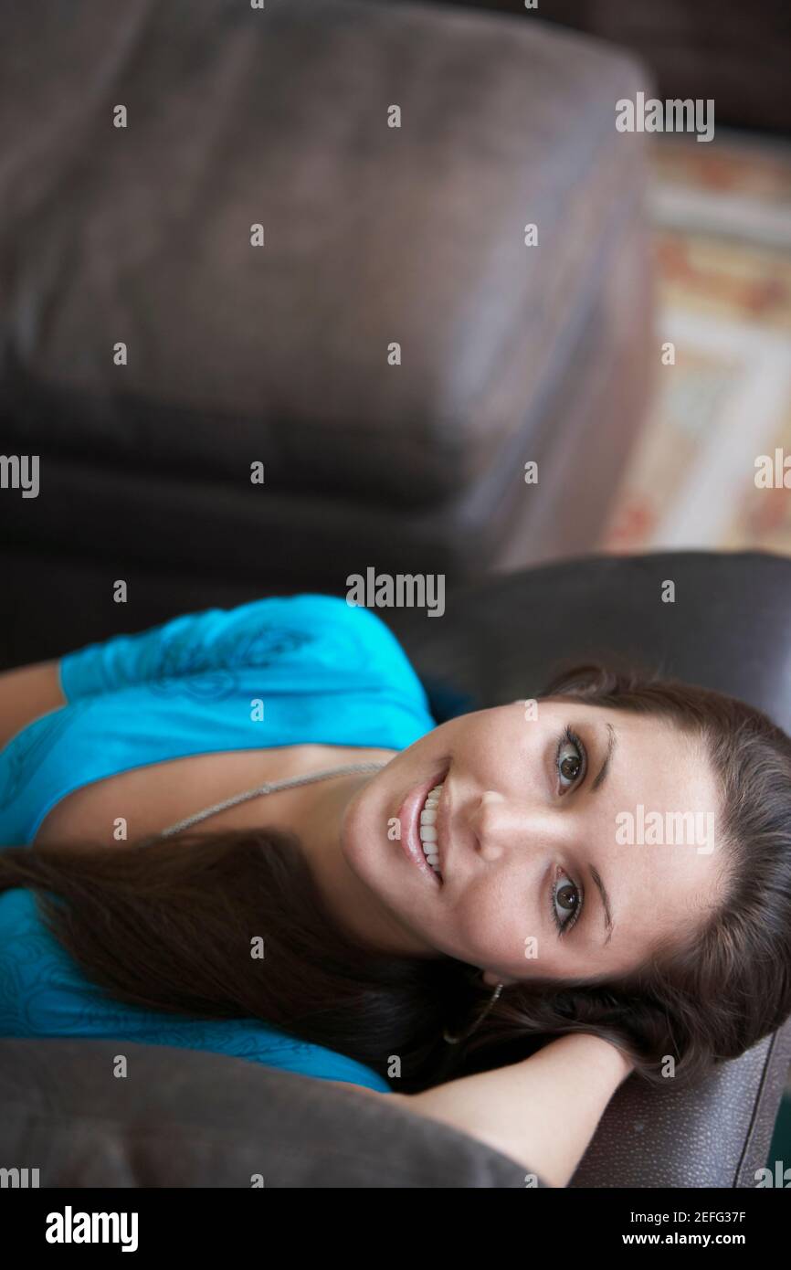Portrait of a young woman lying on a couch and smiling Stock Photo - Alamy