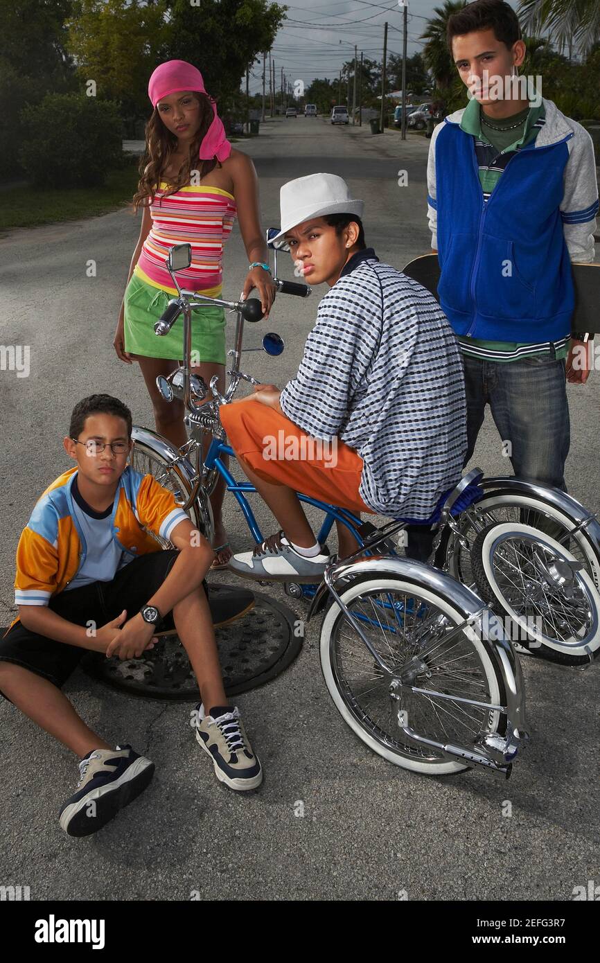 Portrait of a teenage boy on a low rider bicycle with his three friends beside him Stock Photo