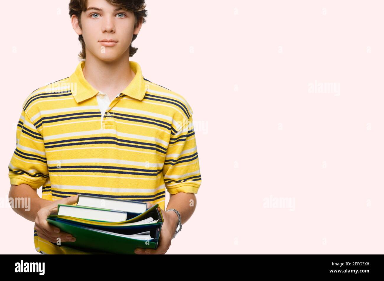 Portrait of a teenage boy holding books and ring binders Stock Photo ...