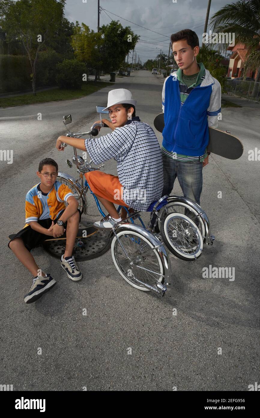 Portrait of a teenage boy on a low rider bicycle with his two friends beside him Stock Photo