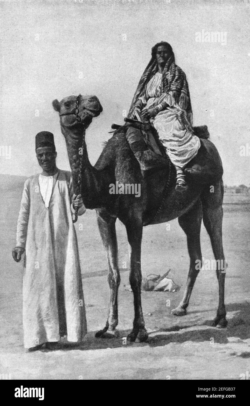 Early 20th century photo of a woman riding a camel in the Sudan as part of a camel caravan circa early 1900s Stock Photo