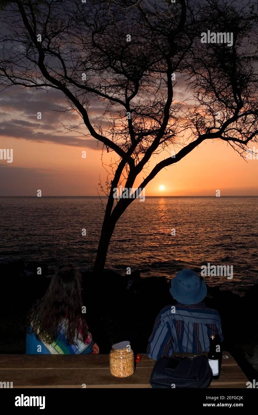 Man and a woman looking at sunset over the sea, Pakini Nui Wind Project, South Point, Big Island, Hawaii Islands, USA Stock Photo