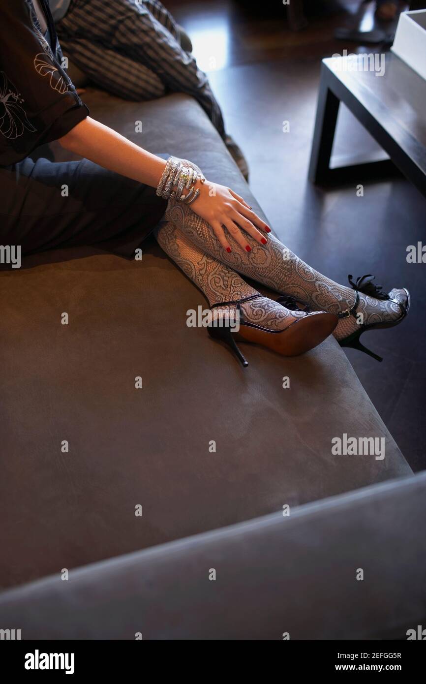 Low section view of a woman sitting on a couch Stock Photo - Alamy