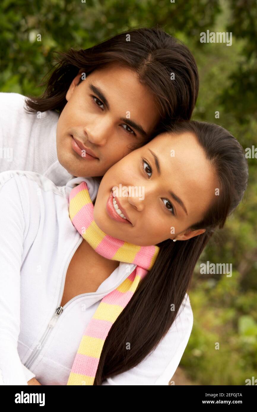 Portrait of a young man embracing a young woman from behind Stock Photo ...