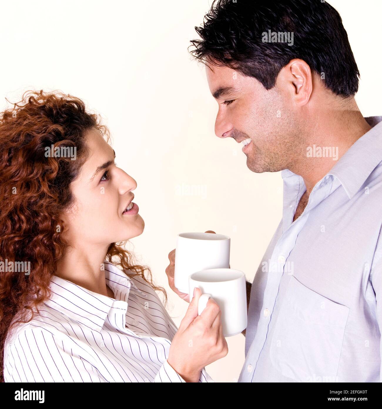Side profile of a young woman and a mid adult man holding coffee cups ...