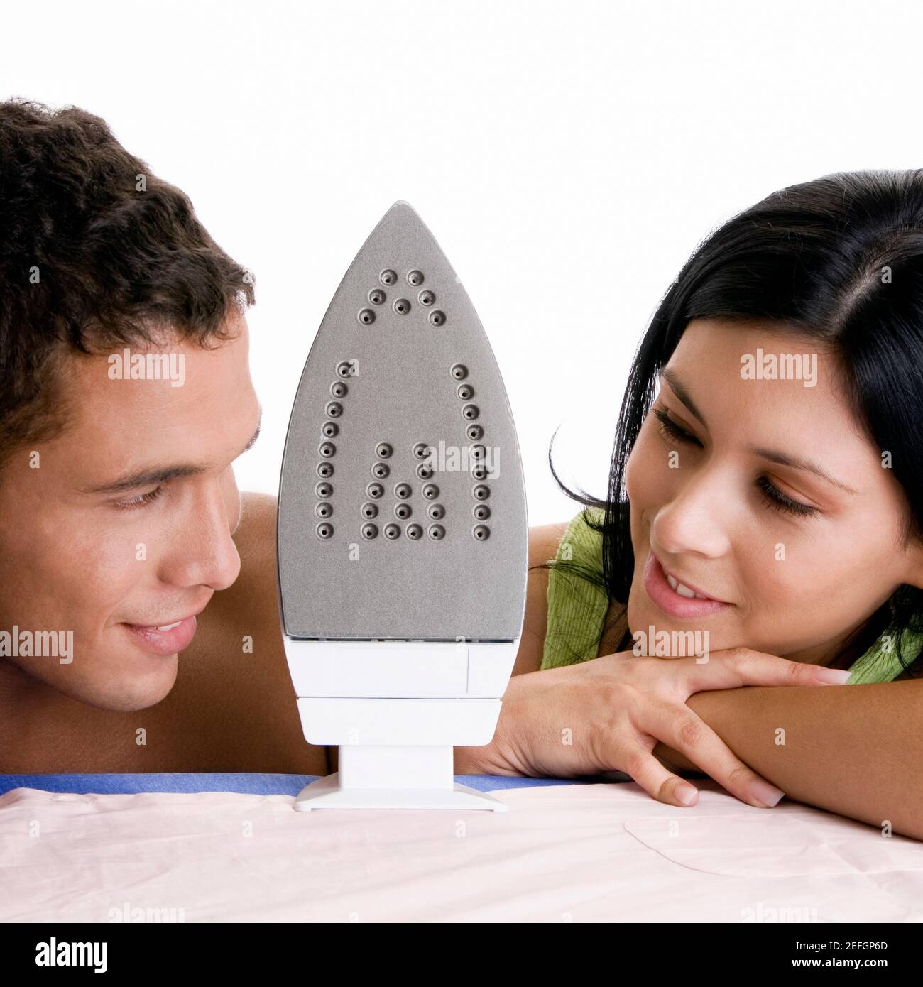 Close-up of a young couple looking at each other with an iron between them Stock Photo