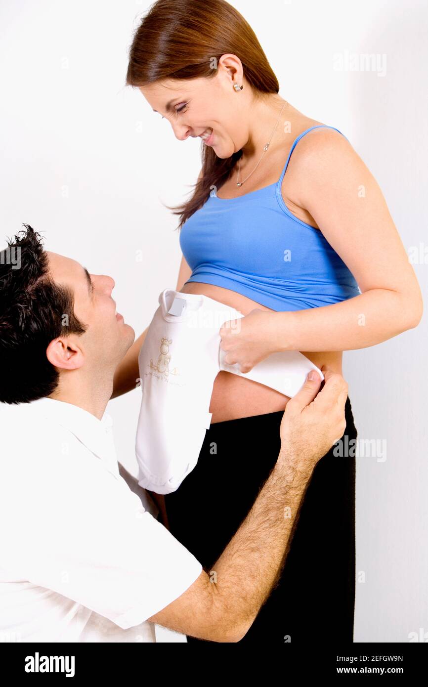 Side profile of a mid adult man and a young woman holding an onesie and ...