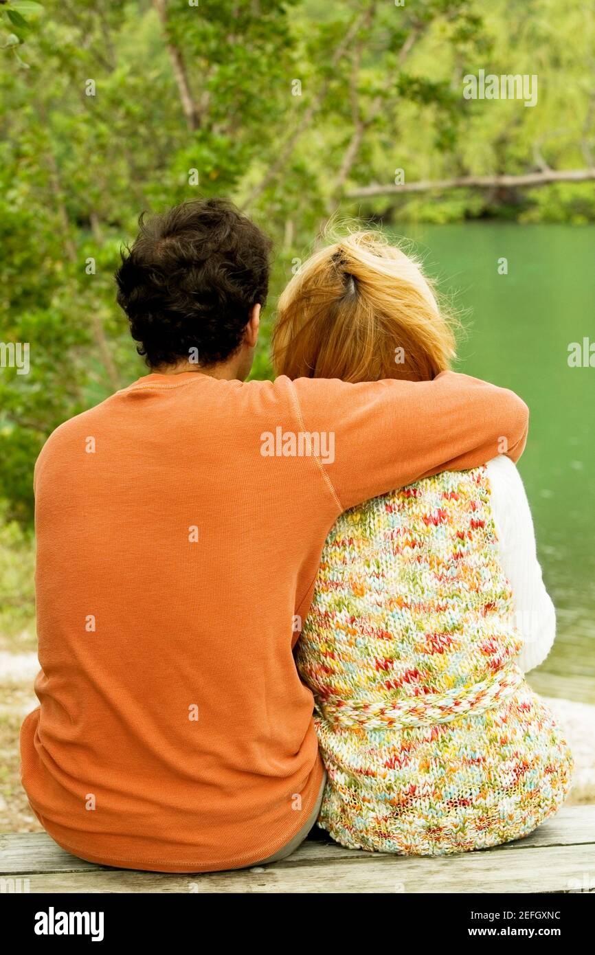 Rear view of a mid adult man sitting with his arm around a young woman ...