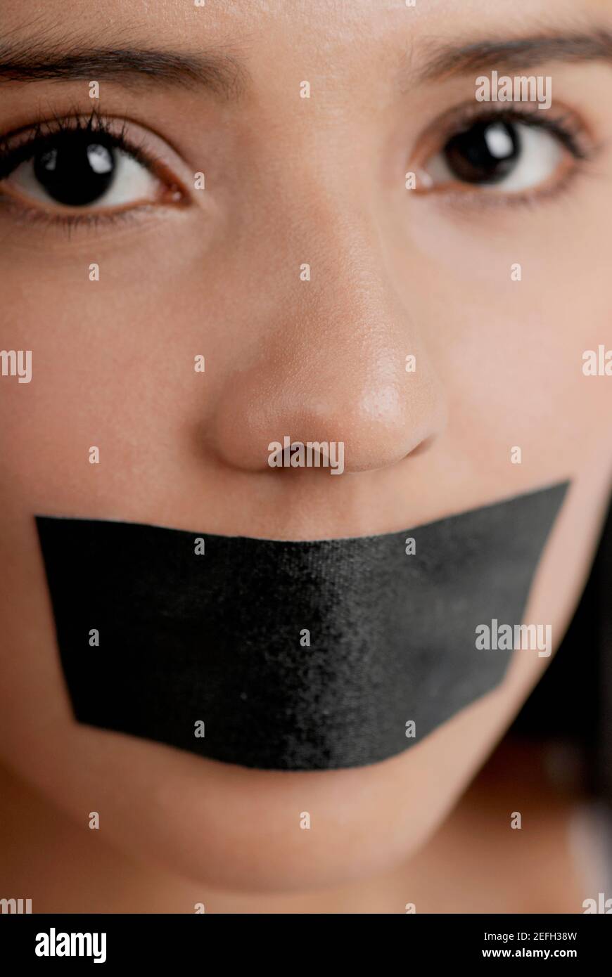 Portrait of a young woman with adhesive tape over her mouth Stock Photo