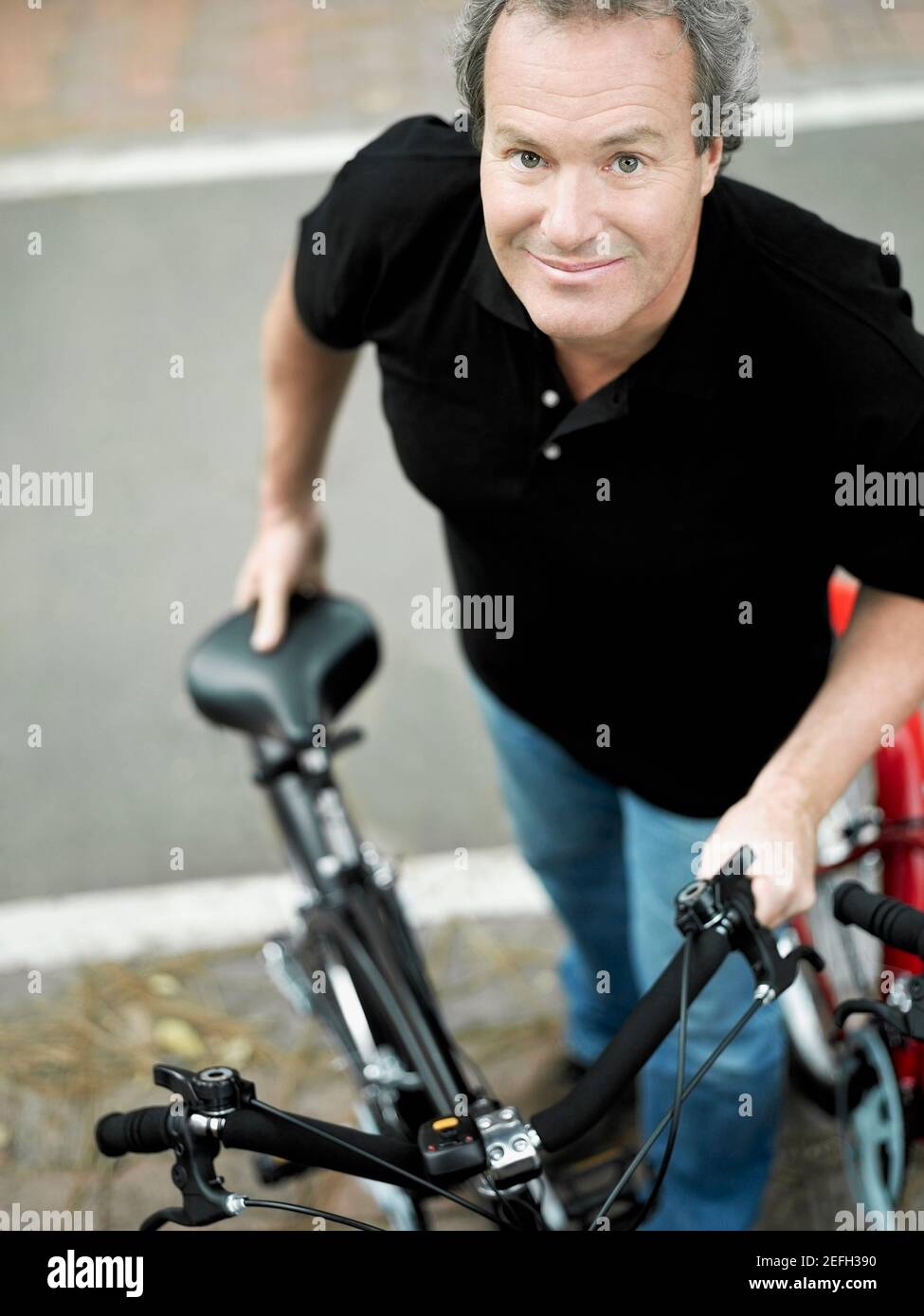 Portrait of a mature man standing with a bicycle Stock Photo
