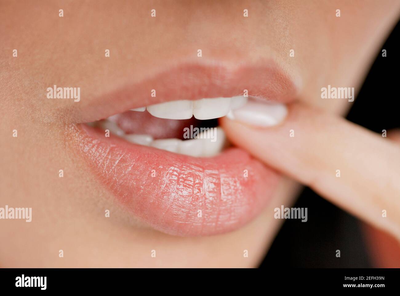 Close-up of a young woman biting her finger Stock Photo