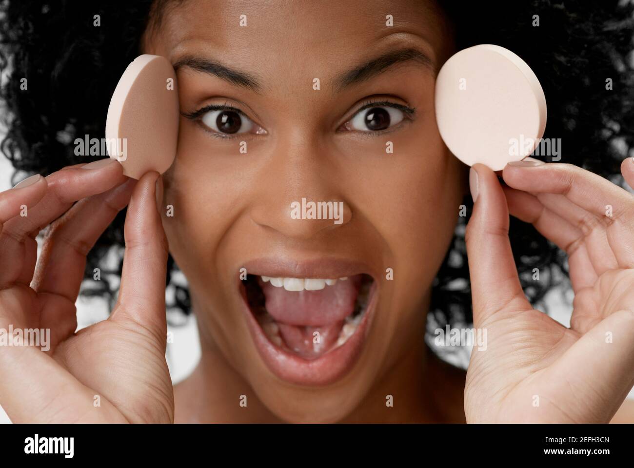 Portrait of a young woman holding powder puffs Stock Photo