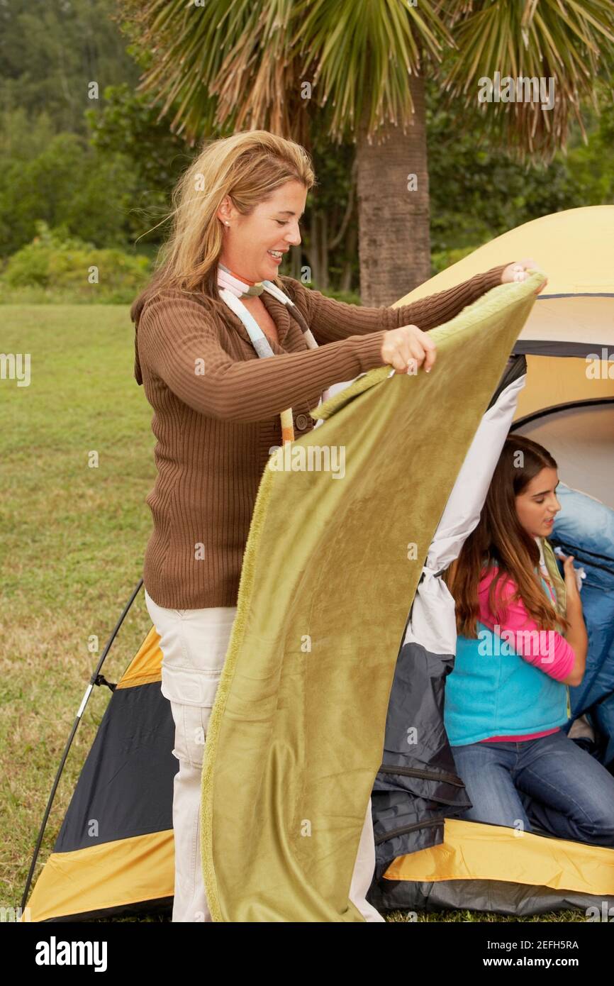 Side profile of a mid adult woman holding a blanket with her daughter near a tent Stock Photo