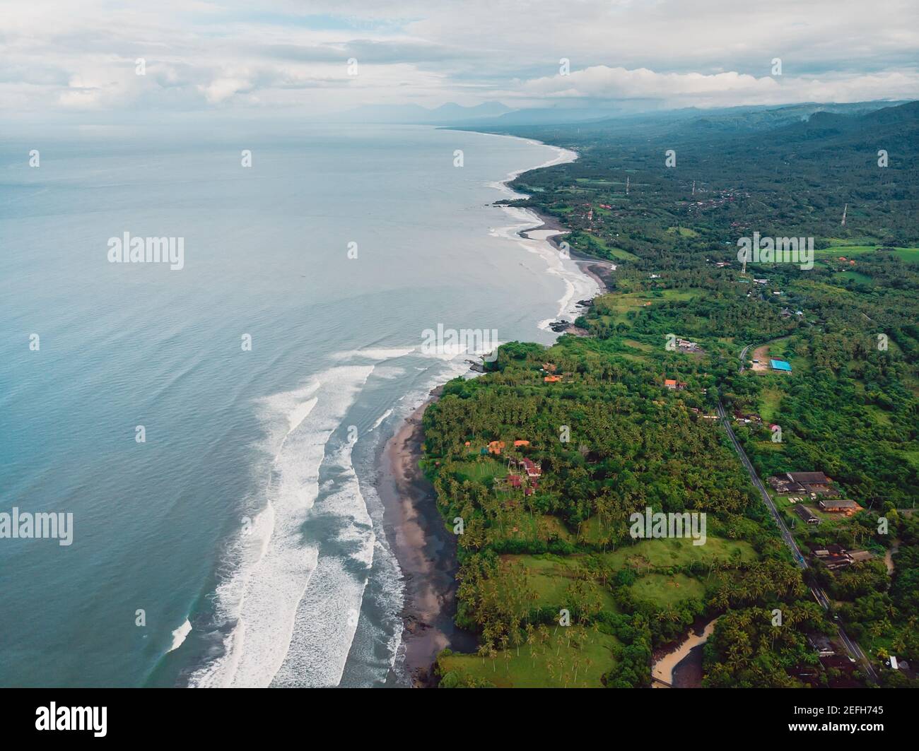 Aerial view of coastline with black sand beaches and waves in Balian, Bali Stock Photo