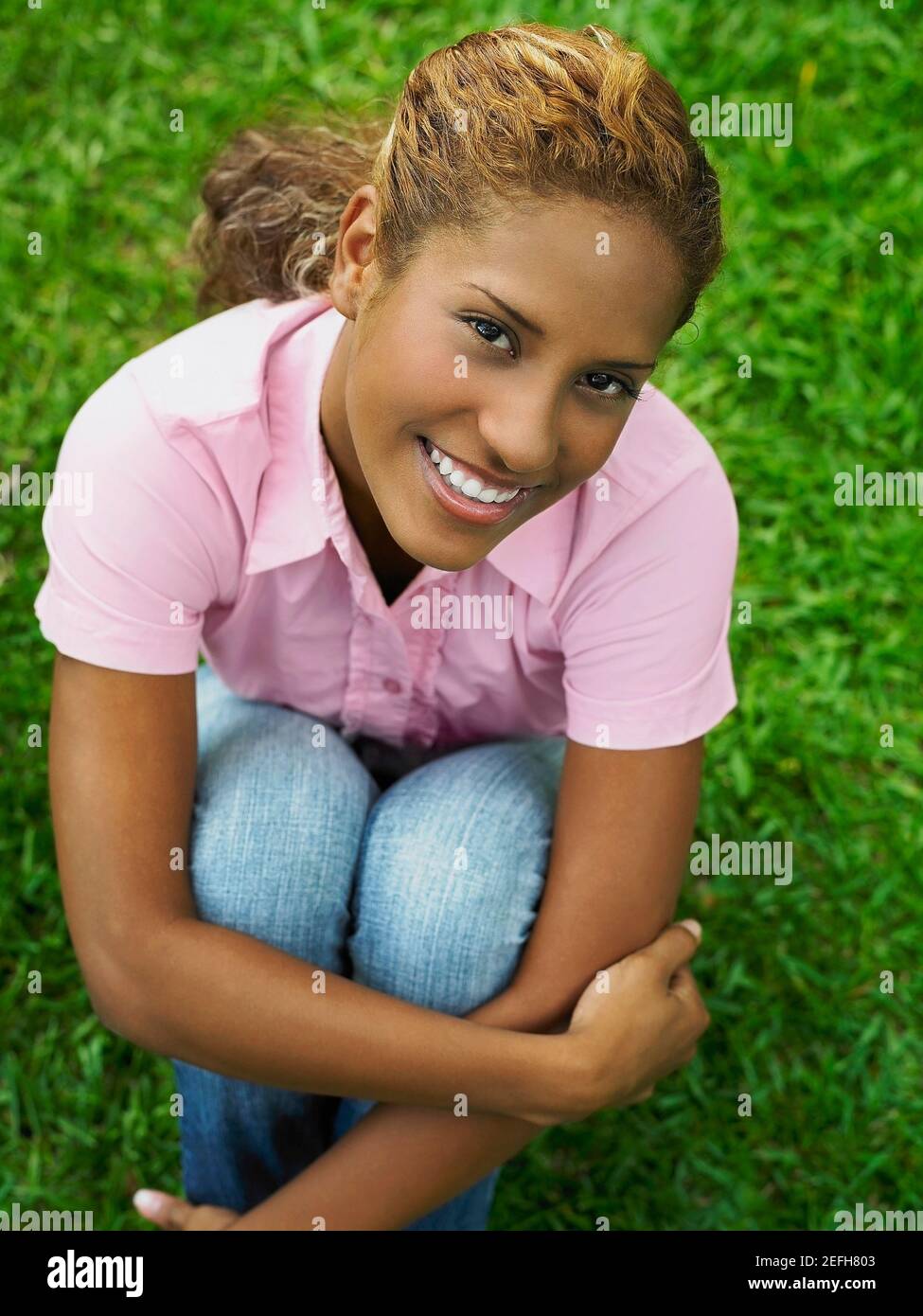 High angle view of a young woman hugging her knees Stock Photo