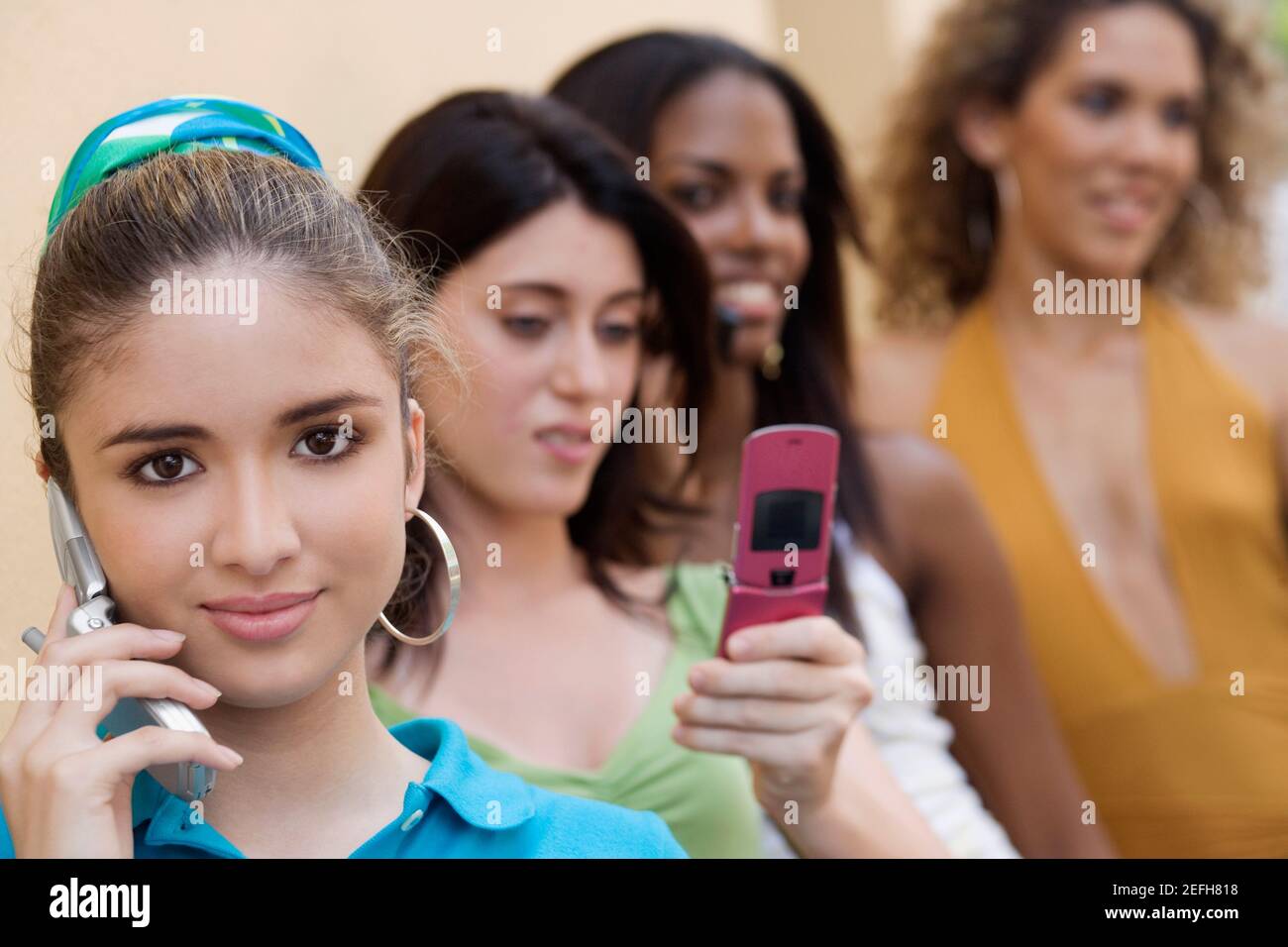 Portrait of a teenage girl talking on a mobile phone with three teenage girls behind her Stock Photo