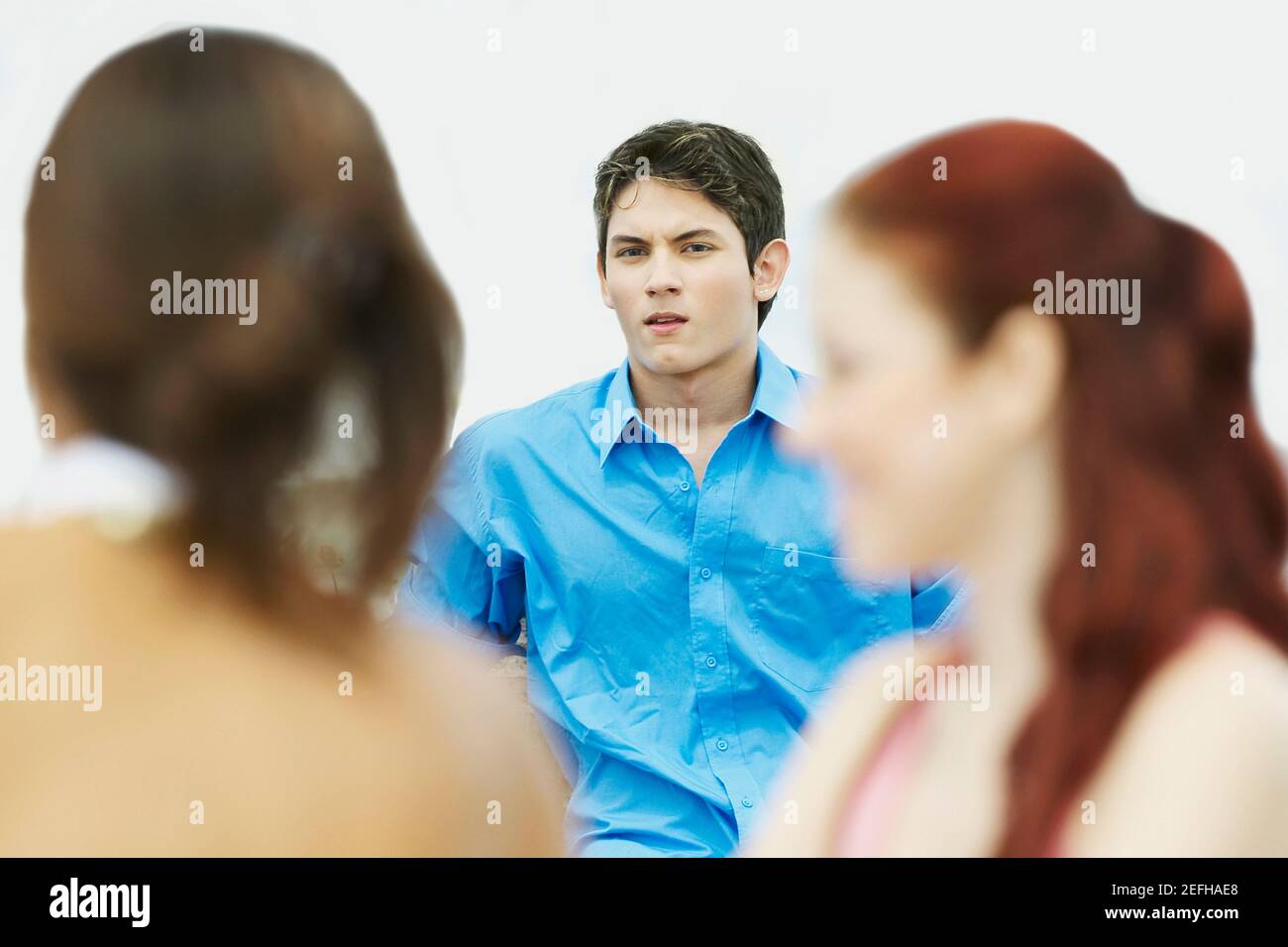 Portrait of a young man sitting with two young women Stock Photo - Alamy
