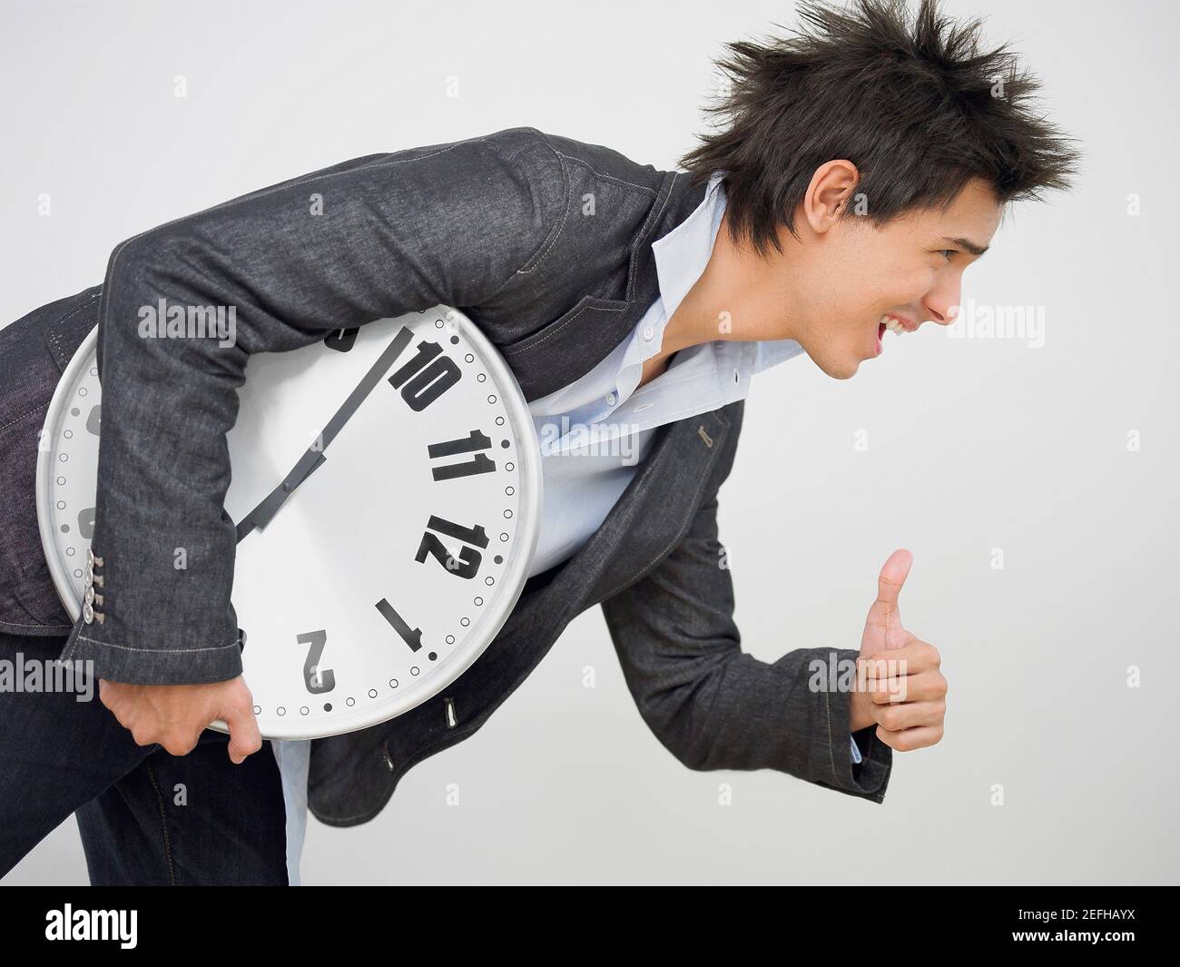 Young man holding a clock and making a thumbs up sign Stock Photo - Alamy