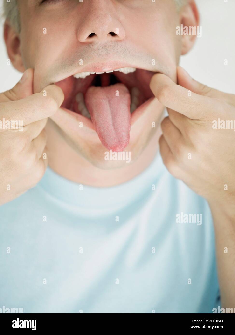 Close up of a young man stretching his mouth and sticking his tongue