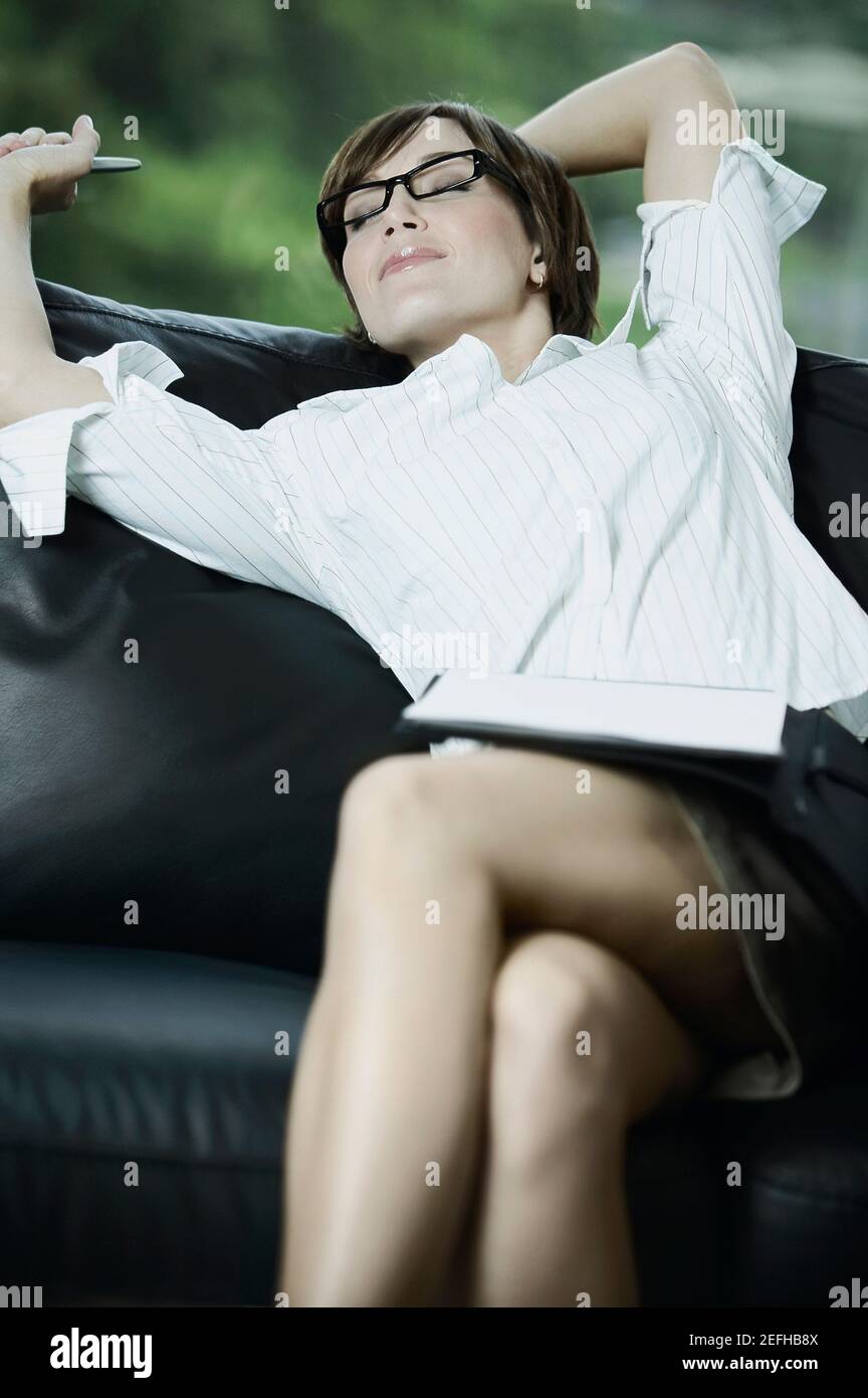 Businesswoman stretching her arms on a couch Stock Photo