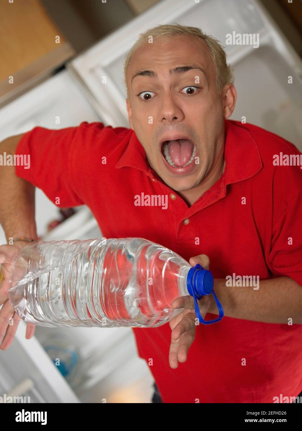 Young man looking at a water bottle slipping from his hands Stock Photo