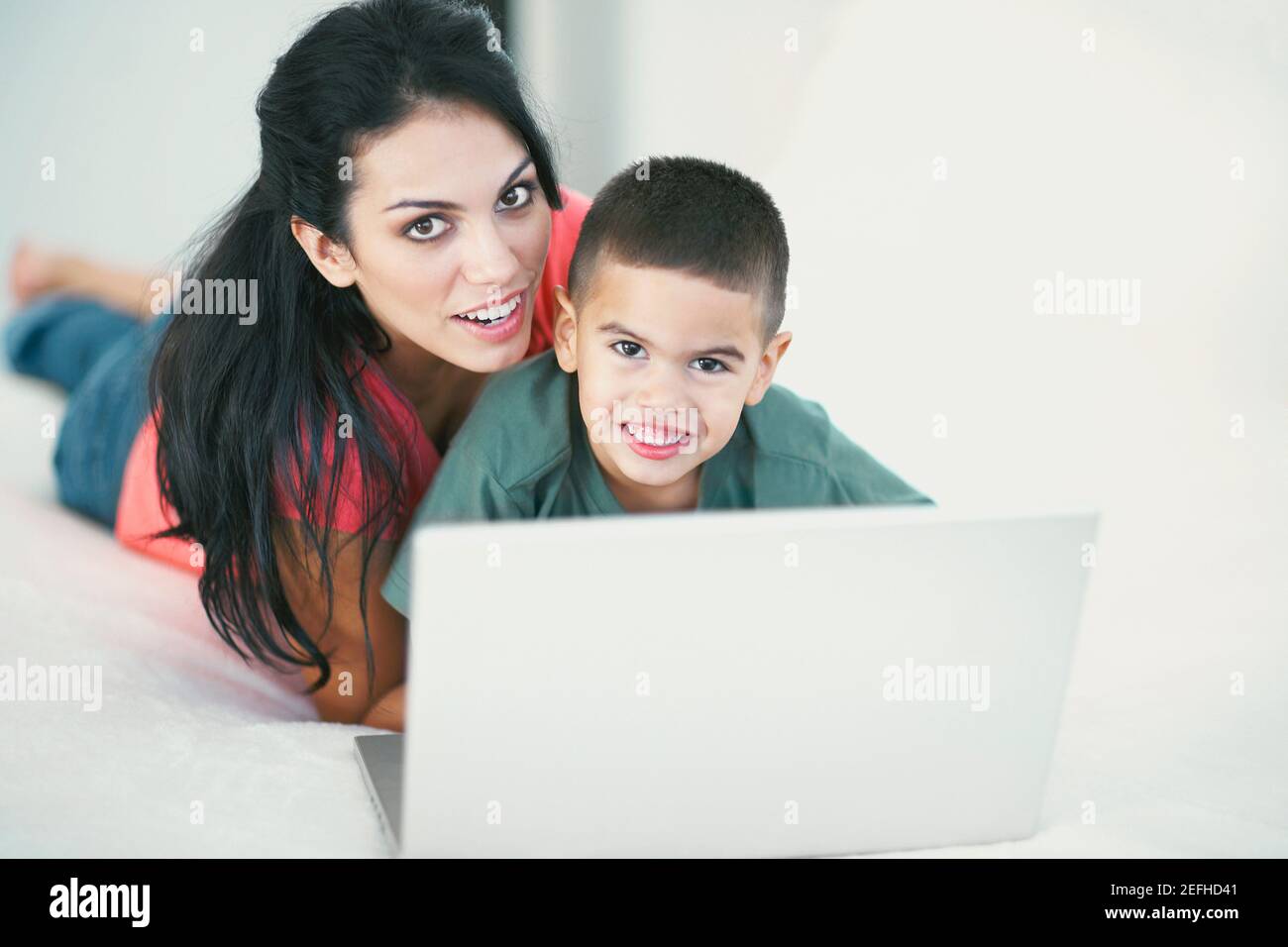 Portrait of a boy and his mother smiling in front of a laptop Stock Photo