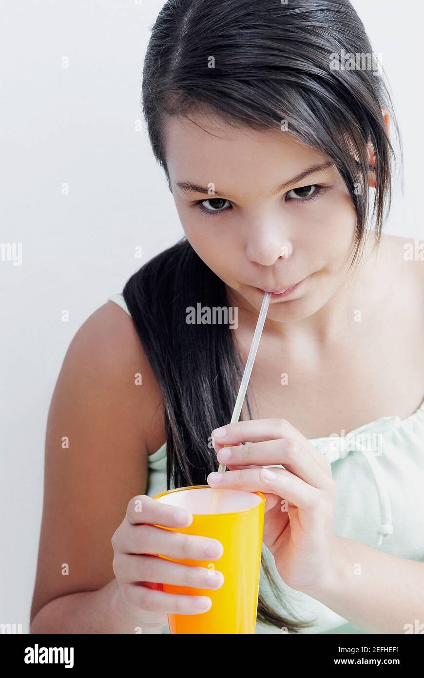 Portrait of a teenage girl drinking water with a drinking straw Stock
