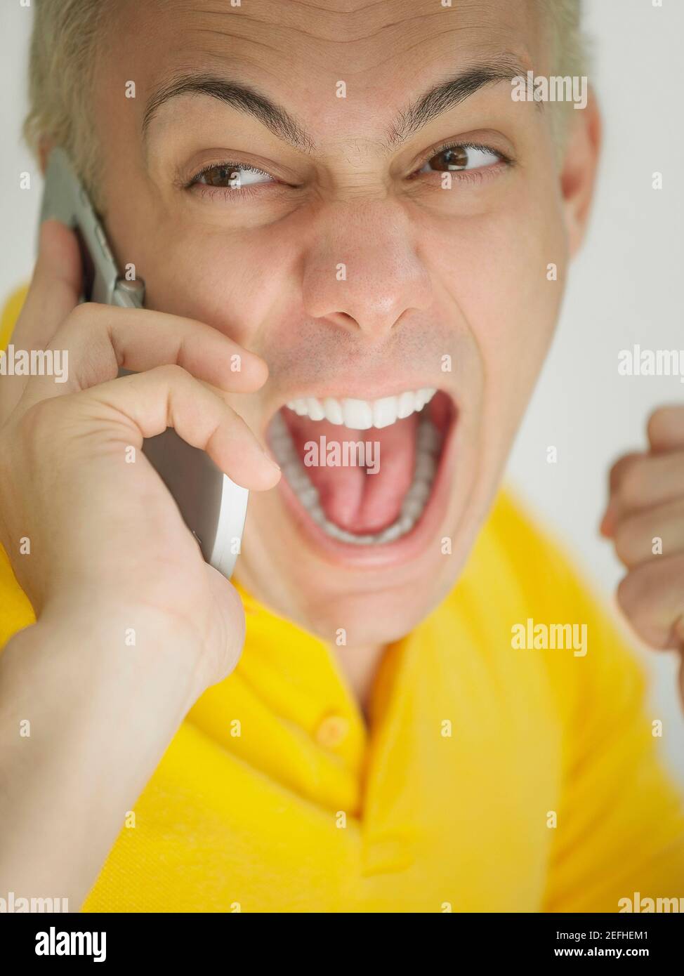 Close up of a young man screaming on a mobile phone Stock Photo
